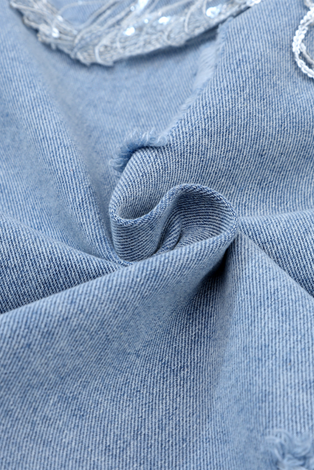 Hemelsblauwe denimjas met pailletten en franjes in een verweerde look