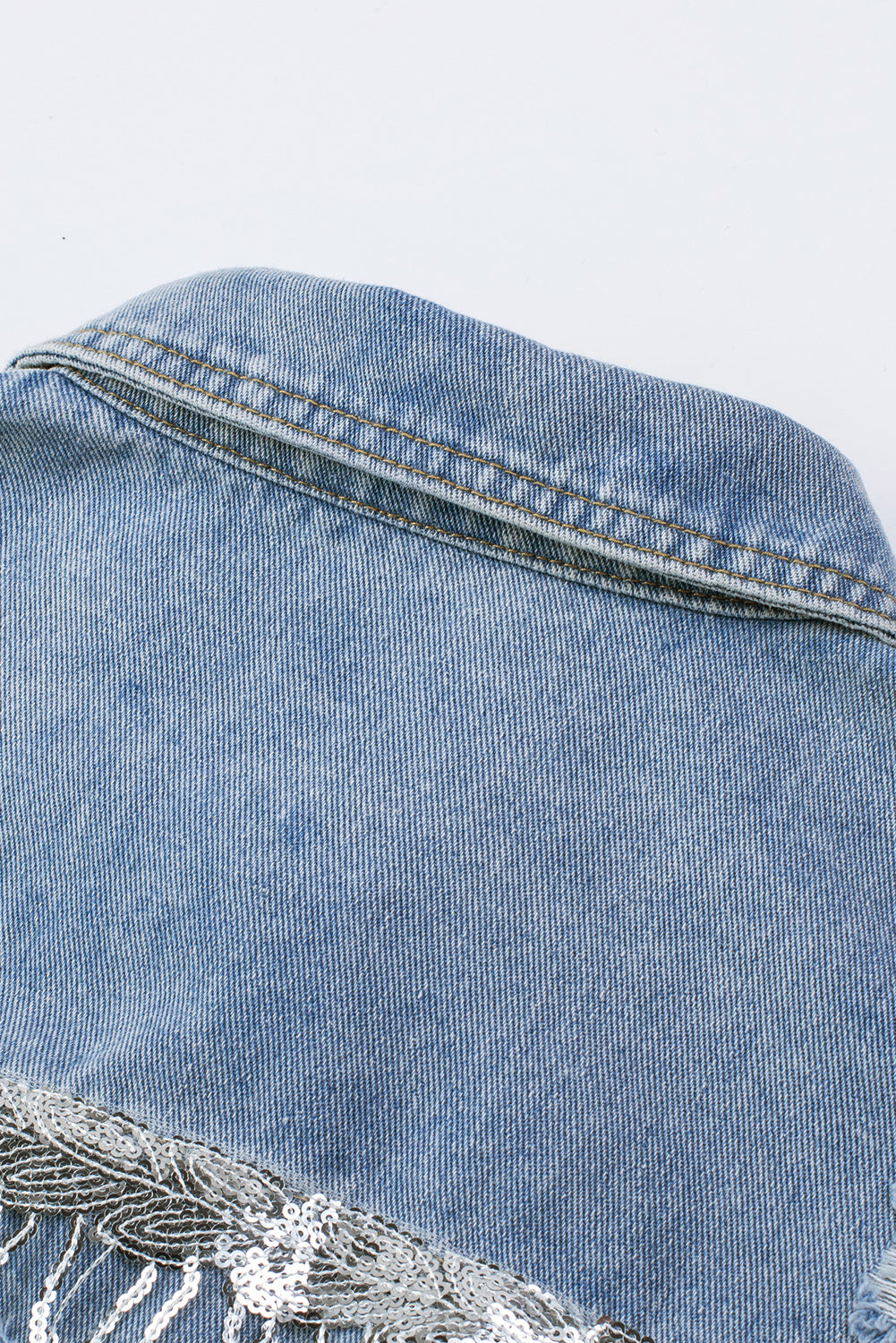 Hemelsblauwe denimjas met pailletten en franjes in een verweerde look